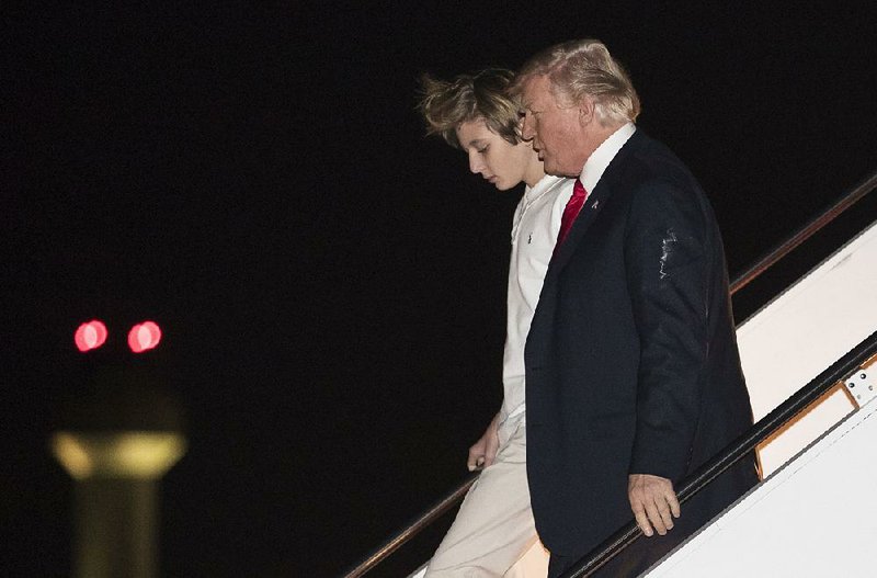 President Donald Trump departs Air Force One with his son, Barron, as they arrive Friday night at the airport in West Palm Beach, Fla., for the weekend. Trump later took to Twitter to rail against what he called the “Russian Witch Hunt.”  