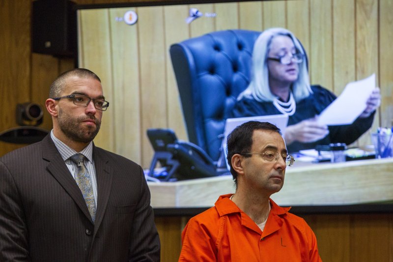 Larry Nassar, right, listens near defense attorney Matthew Newberg as Judge Janice Cunningham (pictured on the monitor) sentences Nassar at Eaton County Circuit Court in Charlotte, Mich., Monday, Feb. 5, 2018. The former Michigan State University sports-medicine and USA Gymnastics doctor received 40 to 125 years for three first degree criminal sexual abuse charges related to assaults that occurred at Twistars, a gymnastics facility in Dimondale. Nassar has also been sentenced to 60 years in prison for three child pornography charges in federal court and between 40 to 175 years in Ingham County for seven counts of criminal sexual conduct. (Cory Morse /The Grand Rapids Press via AP)