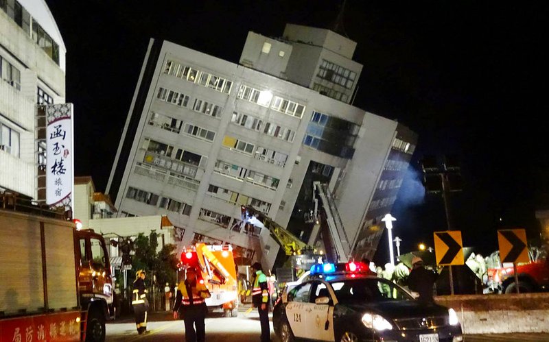 Rescuers are seen entering a building that collapsed onto its side from an early morning 6.4 magnitude earthquake in Hualien County, eastern Taiwan, Wednesday, Feb. 7 2018.  Rescue workers are searching for any survivors trapped inside the building. 