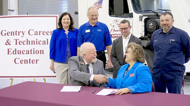 Westside Eagle Observer/RANDY MOLL Blake Robertson, president of Northwest Technical Institute, shakes hands with Terrie Metz, superintendent of the Gentry School District, on Jan. 31 after signing an agreement to offer college credit to graduating Gentry High School students who complete the course of study offered at the school in medium- and heavy-duty truck maintenance and repair. Standing behind Robertson and Metz were Christie Toland, assistant superintendent of Gentry Schools; Carl Desens, NTI instructor and department chair; Brae Harper, principal of Gentry High School Conversion Charter; and Tyson Sontag, instructor for the Gentry diesel mechanic courses taught in the new Gentry Career Education Center.