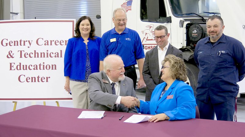 Westside Eagle Observer/RANDY MOLL Blake Robertson, president of Northwest Technical Institute, shakes hands with Terrie Metz, superintendent of the Gentry School District, on Jan. 31 after signing an agreement to offer college credit to graduating Gentry High School students who complete the course of study offered at the school in medium- and heavy-duty truck maintenance and repair. Standing behind Robertson and Metz were Christie Toland, assistant superintendent of Gentry Schools; Carl Desens, NTI instructor and department chair; Brae Harper, principal of Gentry High School Conversion Charter; and Tyson Sontag, instructor for the Gentry diesel mechanic courses taught in the new Gentry Career Education Center.