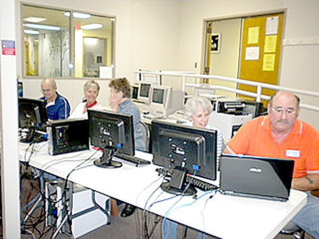 Photo submitted Volunteer Computer Club members work on devices brought in to their training center in the Highlands Crossing building.