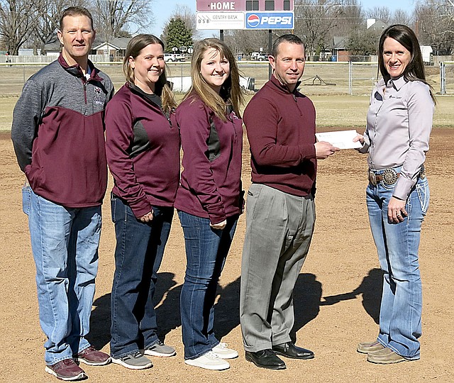 Westside Eagle Observer/RANDY MOLL Savannah Dickinson, vice president and branch manager of Farm Credit of Western Arkansas (right), presents a check to Brae Harper, Gentry High School principal and athletic director, for the purchase of a new scoreboard for the softball field in the Merrill Reynolds Memorial Complex at the high school on Friday. Dickinson and Harper were accompanied on the softball field by head softball coach Paul Ernest and assistant coaches Ayla Smartt and Erica Jones.