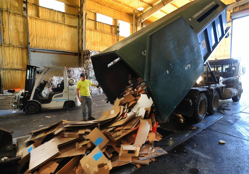 NWA Democrat-Gazette/ANDY SHUPE Christopher Richardson, a driver for the city of Fayetteville's Recycling and Trash Collection Division, helps to unload a hopper of cardboard Feb. 17 at the division's Materials Recovery Facility.