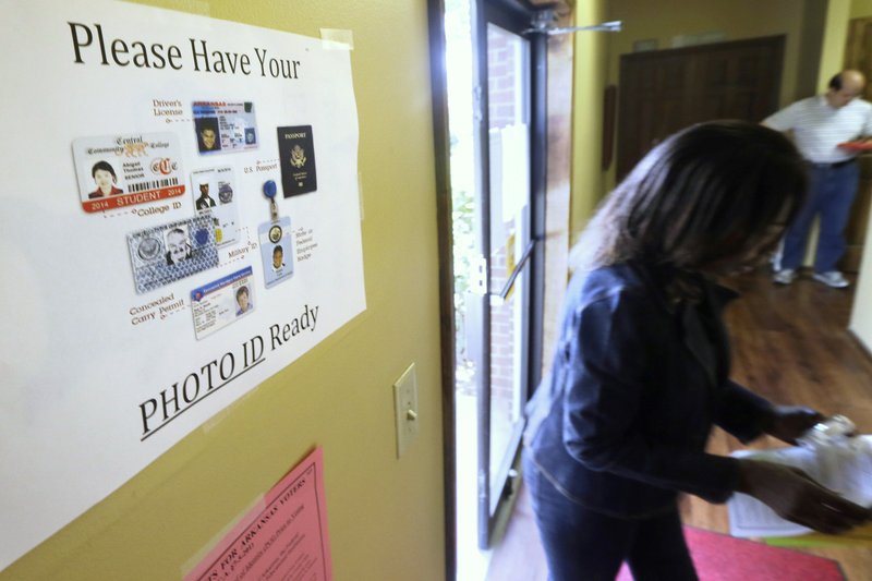 In this May 2014 file photo, an election worker walks past a voter ID sign at a Little Rock polling place. A lawsuit was filed Wednesday challenging the Arkansas Legislature's latest attempt to require that voters show photo identification before casting a ballot. (AP Photo/Danny Johnston, File)