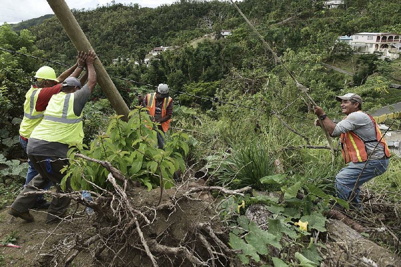 Public works official Ramon Mendez (left) helps municipal workers install a new post to restore electricity to a resident’s home in Coamo in southern Puerto Rico. 