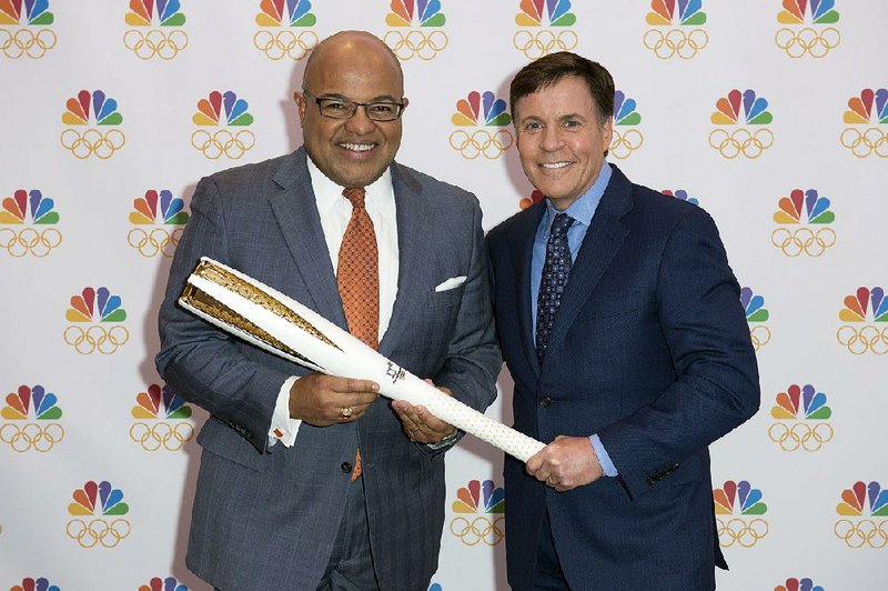 Veteran sports announcer Bob Costas (right) hands the Olympic torch to Mike Tirico, who will make his debut as NBC’s prime-time Olympics host at The Winter Olympics in PyeongChang.
