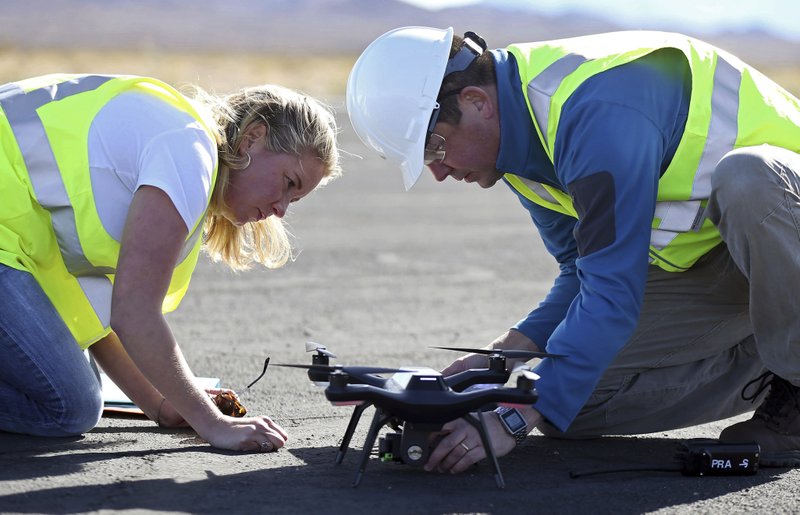 Jessica Balik, left, and Keven Gambold, right, CEO of Unmanned Experts, prepare a drone for a demonstration at the Searchlight airport in Searchlight, Nev., on Wednesday, Jan. 17, 2018. (AP Photo/Isaac Brekken)