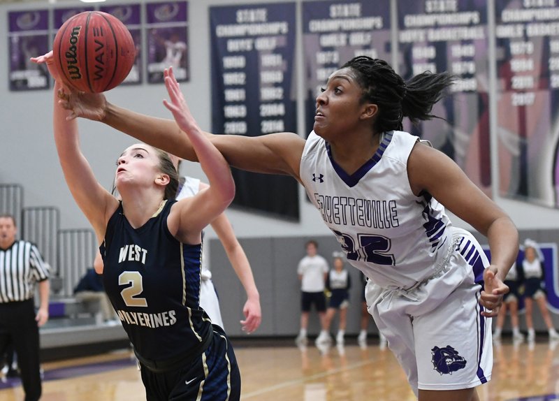 Fayetteville's Jasmine Franklin (right) tries to knock the ball away from Bentonville West's Allie Clifton on Wednesday at Bulldog Arena in Fayetteville.
