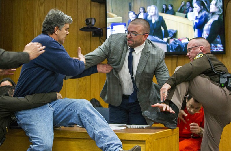 Randall Margraves, left, father of three victims of Larry Nassar, background right, lunges at Nassar in Eaton County Circuit Court in Charlotte, Mich., on Friday, Feb. 2, 2018. The incident came during the third and final sentencing hearing for Nassar on sexual abuse charges. The charges in this case focus on his work with Twistars, an elite Michigan gymnastics club. 