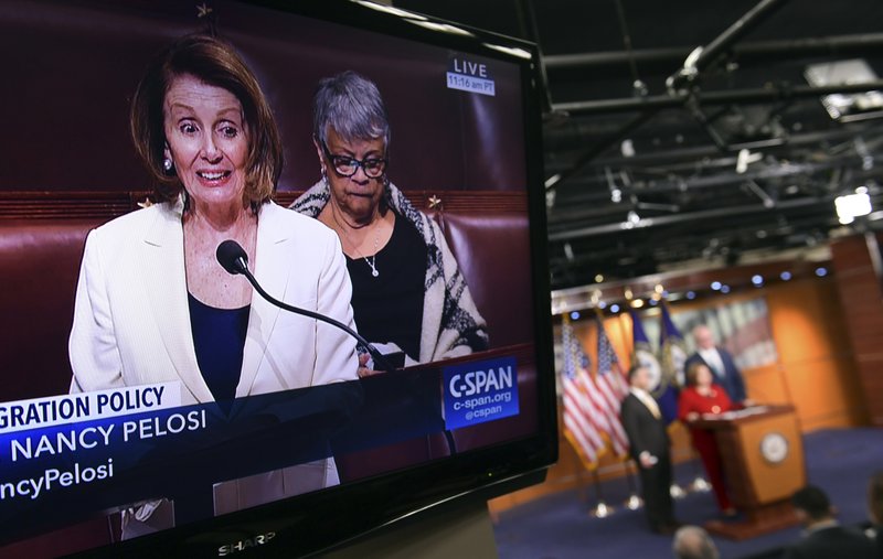 House Minority Leader Nancy Pelosi of Calif., is shown on television as she speaks from the House floor on Capitol Hill in Washington, Wednesday, Feb. 7, 2018, as a news conference that she was supposed to attend goes on in the background. 