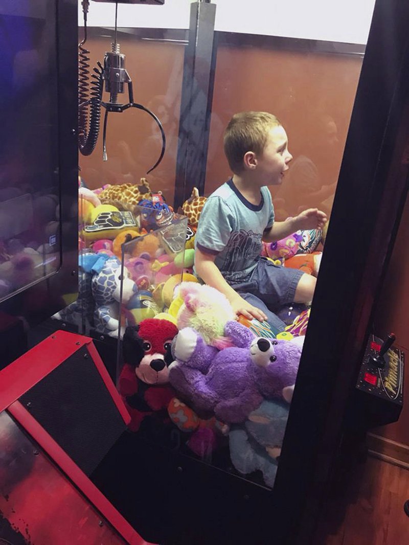 This photo made available by the Titusville Fire and Emergency services shows fire fighters attempting to rescue a boy who crawled inside a claw-style vending machine, Wednesday, Feb. 7, 2018, in Titusville, Fla. The boy sat atop the stuffed toys while firefighters took just 5 minutes to get him out. (Titusville Fire and Emergency Services via AP)

