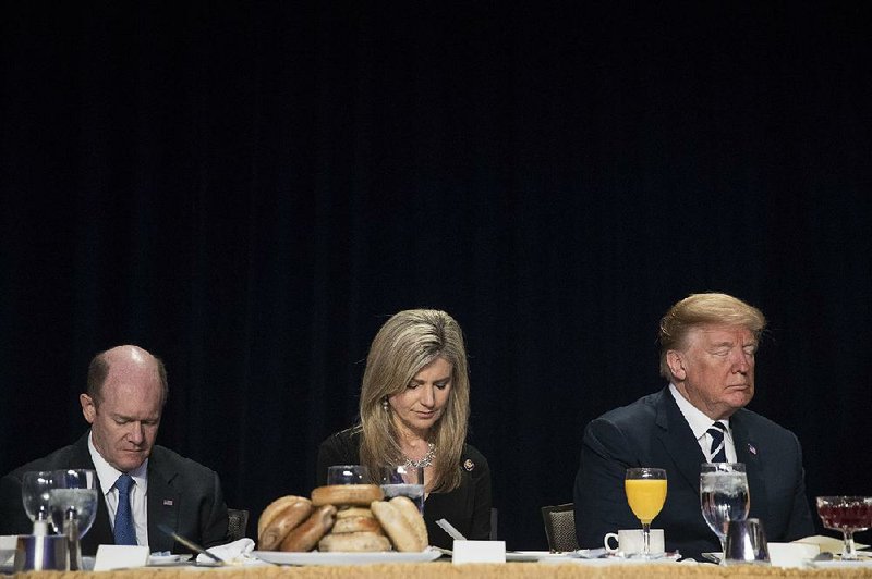 President Donald Trump joins in prayer Thursday in Washington with Sen. Chris Coons, D-Del., and Christy Hultgren, wife of Rep. Randy Hultgren, R-Tenn. 