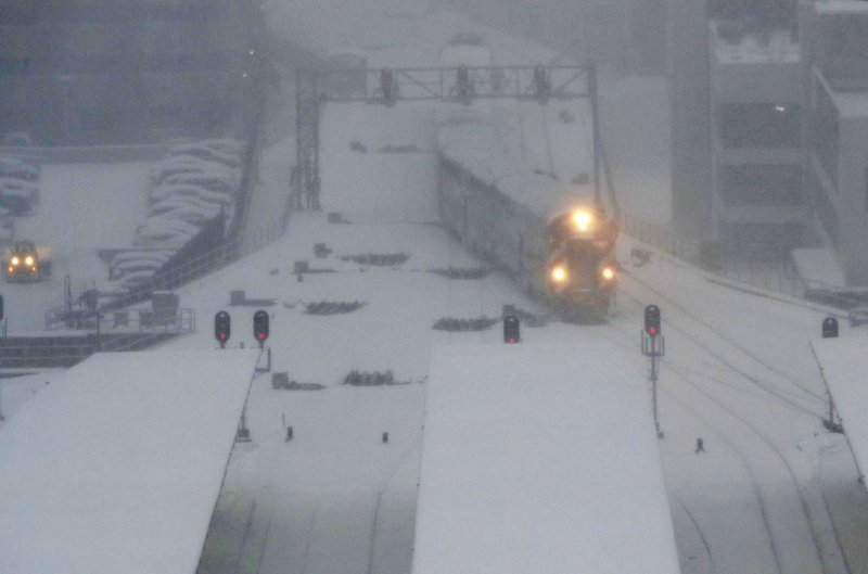 A commuter train pulls into the LaSalle Street station under a heavy snow fall early Friday, Feb. 9, 2018, in Chicago. The National Weather Service issued winter-weather warnings and advisories across the upper Midwest. The snow that began falling late Thursday afternoon was expected to continue through Friday as the storm moves east. 