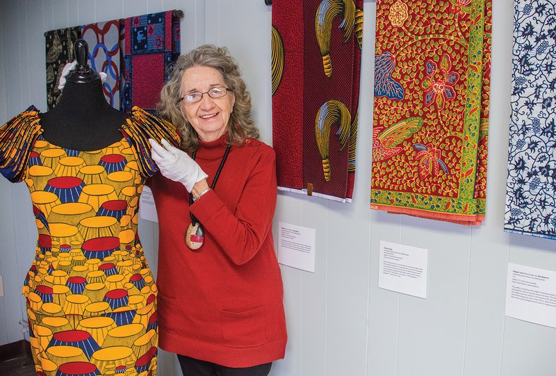 Farrell Ford, executive director of the Clark County Arts and Humanities Council, shows one of the highlights of the traveling art exhibit Wandering Spirit: African Wax Prints that is on display at the Arkadelphia Arts Center. This King’s Chair dress form, created in 1980, is part of the exhibit, courtesy of the Beatrice Benson Collection. Visitors to the exhibit are not allowed to touch the fabrics with their bare hands but will be issued gloves similar to those Ford is wearing.
