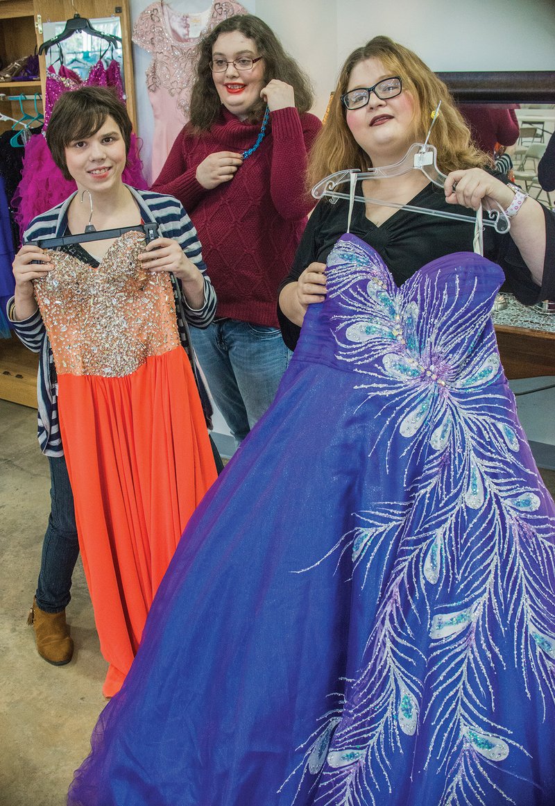 Arkadelphia Human Development Center resident Candie Jo Butler, center, shows a possible jewelry selection, while residents Kelsey Heffner, left, and Hannah White show possible ball-gown selections for Winter Wonderland Prom 2018. Formalwear for women and men, shoes, accessories, flowers, hairstyling and other services have been donated for Saturday’s event.