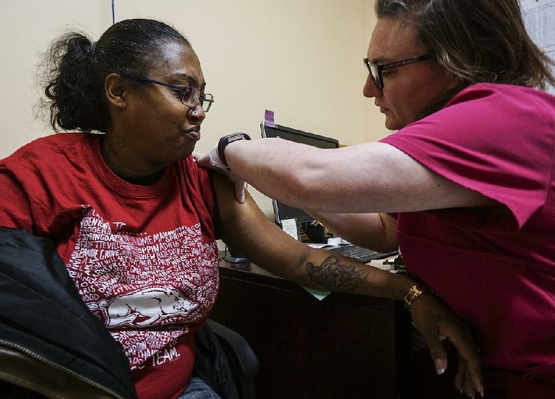 Amanda Butler of Little Rock gets her flu shot from nurse coordinator Miranda Tucker at the Pulaski County unit of the state Health Department in Little Rock.