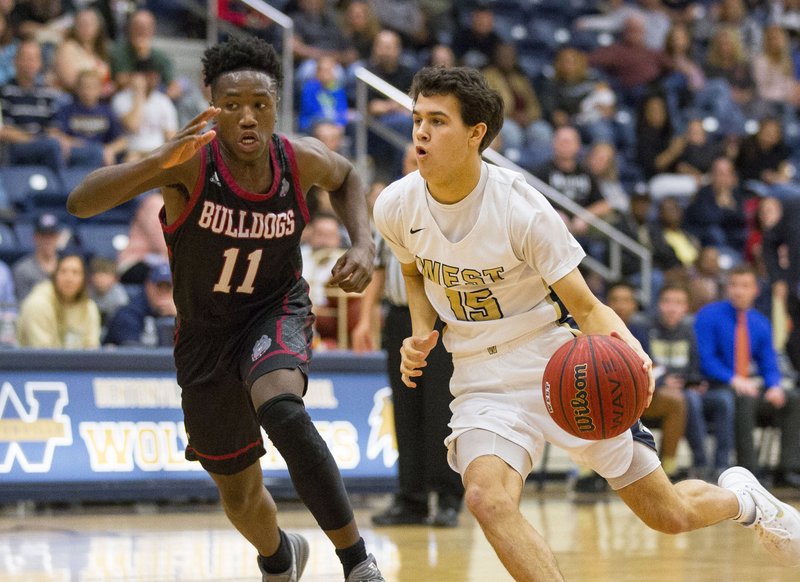 Garrett Wilmot (right) of Bentonville West drives to the basket as Springdale High’s Marquis Donahoo defends Friday at Wolverine Arena in Bentonville.