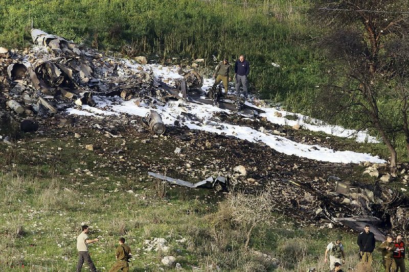 Israeli security forces stand guard Saturday at the wreckage of an F-16 that crashed in northern Israel after it was hit by anti-aircraft fire while returning from a bombing mission deep in Syrian territory. The two crewmen ejected, and one was seriously injured.