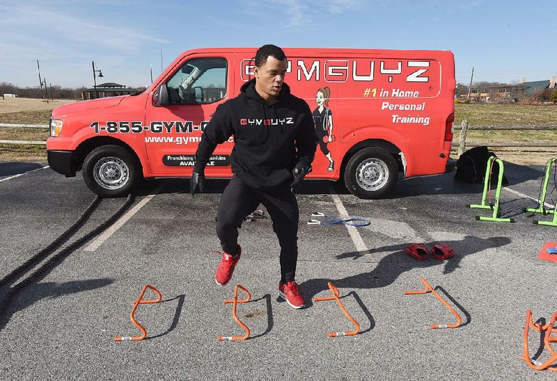 Phoenix Johnson, the fitness coach for the Gymguyz Bentonville franchise, demonstrates an aerobic workout using equipment carried in the company van.
