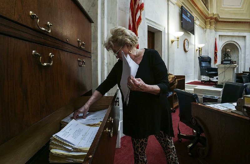 At the state Capitol on Wednesday, bill custodian JoAnn Drew sorts through appropriation bills that will be introduced in the Senate when the legislative fiscal session begins Monday.