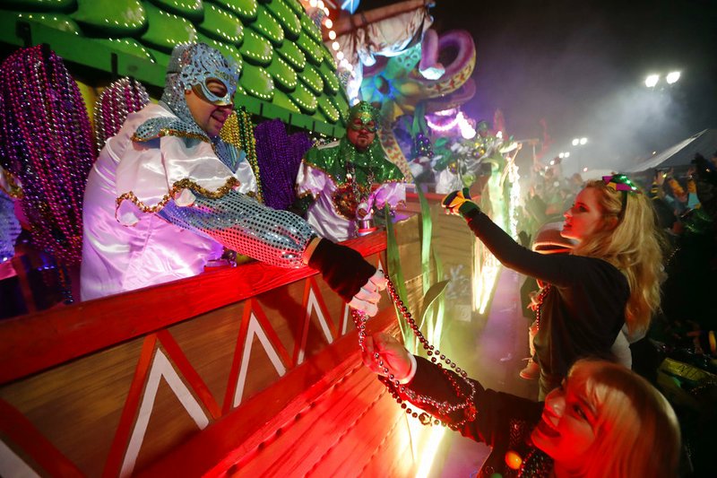 Float riders hand beads to the crowd as the Krewe of Orpheus rolls in New Orleans, Monday, Feb. 12, 2018. Tens of thousands of revelers are expected on New Orleans streets for parades and rowdy fun as Mardi Gras caps the Carnival season in a city with a celebration of its own, its 300th anniversary.