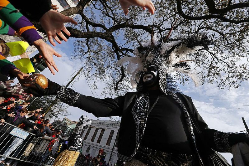 A member of the Zulu Social Aid and Pleasure Club hands out prized painted coconuts Tuesday in New Orleans during the group’s Mardi Gras parade. Tens of thousands of revelers packed the sidewalks for the Zulu and Rex parades and frenzied merrymaking up until midnight, when the police clear the streets and Ash Wednesday begins.  