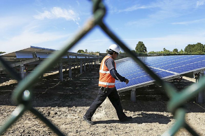 A worker walks past solar panels at a SpaceX facility near Brownsville, Texas, earlier this year. Elon Musk, founder of SpaceX and Tesla, expects Tesla’s solar arm to play an important role in the company’s growth. 