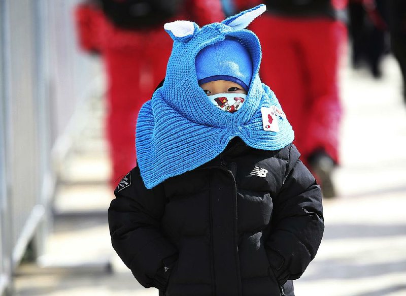 A bundled up girl walks near Phoenix Snow Park at the Winter Olympics. Colder-than-normal temperatures
and strong winds have caused problems for spectators and competitors.