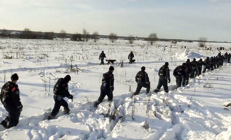 In this photo provided by the Russian Emergency Situations Ministry, emergency teams head to the scene of an AN-148 plane crash near the village of Stepanovskoye on Monday.
