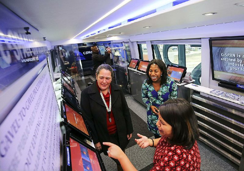 Jenae Green (top right) and Vanessa Torres (bottom) of C-SPAN show visitor Michelle Gibson some of the interactive features aboard the C-SPAN tour bus during its stop Tuesday at the state Capitol.