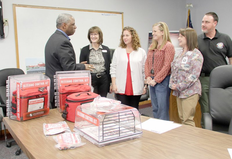 SPENCER TIREY NWA DEMOCRAT-GAZETTE Washington County Judge Joseph Wood, left, prepares to hand out medical kits to area school nurses, Kathy Launder of Springdale, Aimee Silvis of Farmington, Emily Robbins of Lincoln and Melissa Thomas of Fayetteville. A new program called "Stop the Bleed" provides training on proper bleeding control techniques that can be used during emergency situations on school campuses. Standing behind the nurses, John Luther, director of Washington County Emergency Management, said 92 individual schools in Northwest Arkansas will receive the kits.