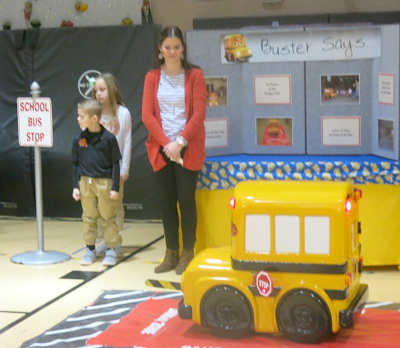 Westside Eagle Observer/SUSAN HOLLAND Liam Pittman and Layla Patton, first graders at Glenn Duffy Elementary School, and first-grade teacher Miss White, participate in the school's assembly featuring Buster the School Bus Tuesday, Feb. 6. Here the students were demonstrating the importance of looking both ways before crossing the street after exiting the bus.
