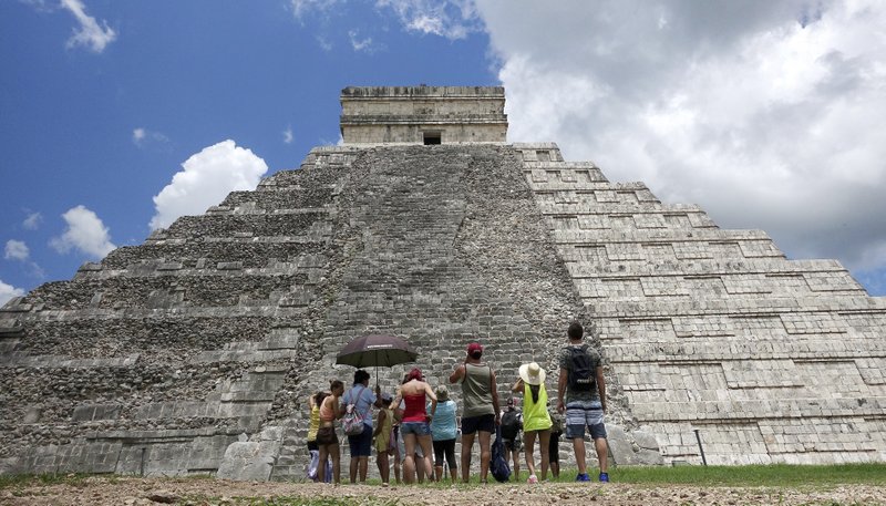In this July 2016 photo, tourists are dwarfed by El Castillo at the Chichen-Itza ruins in Yucatan, Mexico. While beach destinations remain popular for spring break, travel agents say customers are also demanding unique cultural experiences and active outdoorsy adventures. (AP Photo/Ross D. Franklin)