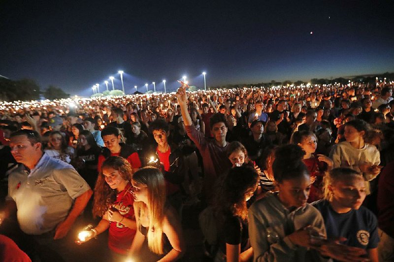 Mourners hold a candlelight vigil Thursday night at Marjory Stoneman Douglas High School in Parkland, Fla. 