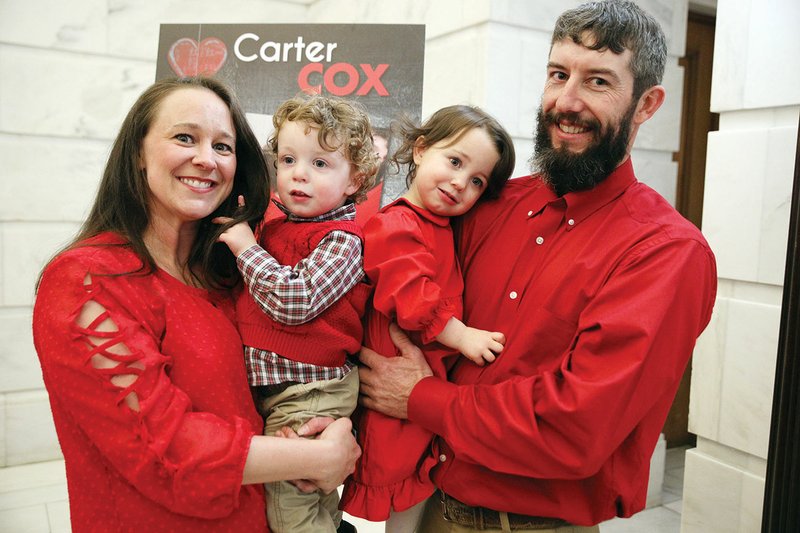 Katie and Lance Cox of Heber Springs hold their 2 1/2-year-old twins, John, left, and Carter at the unveiling Feb. 1 of Carter’s portrait at the state Capitol in Little Rock. Carter was named as one of the honorees of Central Arkansas’ Go Red for Women Survivor Gallery. She and her brother have Long QT syndrome, which causes erratic heartbeats. Katie, a registered nurse, said she wants to educate the public about the syndrome