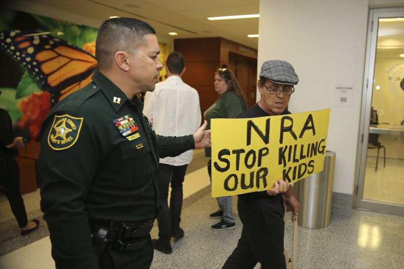 A Broward County sheriff's deputy escorts a protestor away from the door of the courtroom where a hearing was held for school shooting suspect Nikolas Cruz, Thursday, Feb. 15, 2018, at Broward County Court in Fort Lauderdale, Fla. Cruz is accused of opening fire Wednesday at Marjory Stoneman Douglas High School in Parkland, Fla., killing more than a dozen people and injuring several. 