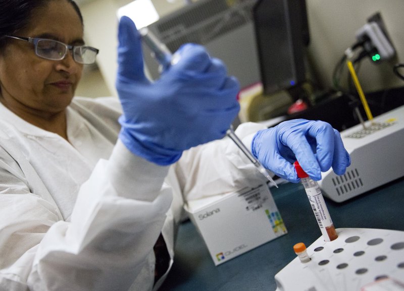 FILE - In this Friday, Feb. 9, 2018 file photo, lab technologist Sharda Modi tests a patient's swab for a flu infection at Upson Regional Medical Center in Thomaston, Ga. On Friday, Feb. 16, 2018, a report released by the Centers for Disease Control and Prevention shows the flu season may finally be leveling off. (AP Photo/David Goldman)