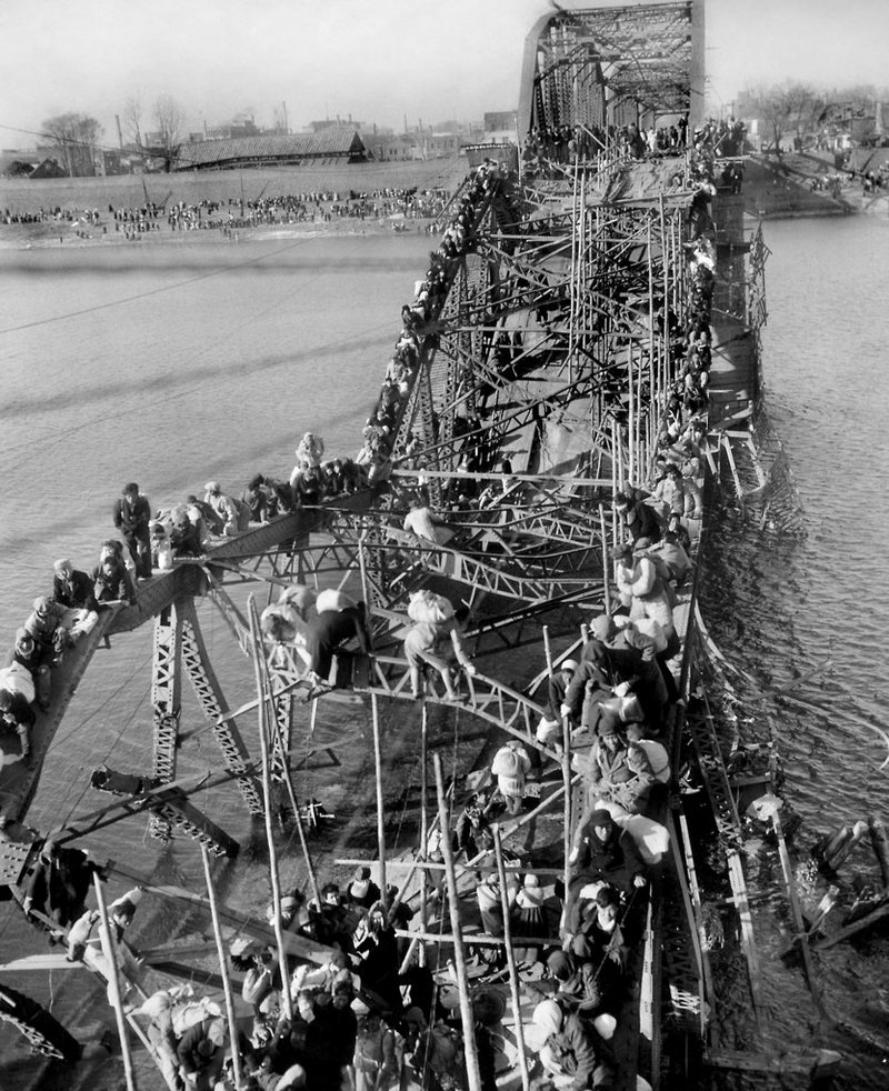 FILE - In this Dec. 4, 1950, file photo, residents from Pyongyang, North Korea, and refugees from other areas crawl perilously over shattered girders of the city's bridge, as they flee south across the Taedong River to escape the advance of Chinese Communist troops. Former Associated Press photographer Max Desfor, whose photo of hundreds of Korean War refugees crawling across a damaged bridge in 1950 helped bring him a Pulitzer Prize, died Monday, Feb. 19, 2018. He was 104. 