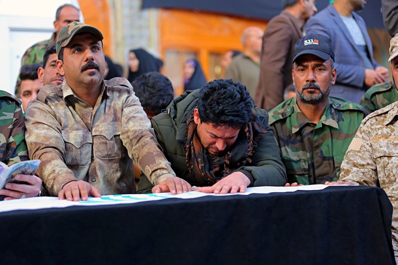 Mourners pray over the flag-draped coffin of Ismail Mahmoud, 24, a fighter of the Popular Mobilization Forces, who was killed Sunday in an attack southwest of the northern city of Kirkuk, during his funeral in Najaf, Iraq, Monday, Feb. 19, 2018. Officials said Monday that Islamic State militants ambushed the group of Iraq's Shiite-led paramilitary fighters, killing Mahmoud and at least 26 others, more than two months after Baghdad declared victory over the extremist group. (AP Photo/Anmar Khalil)