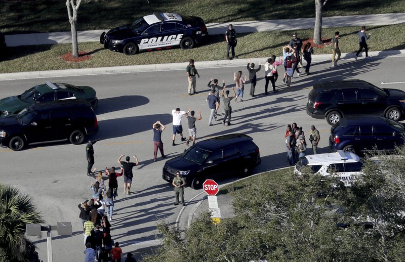 FILE - In a Wednesday, Feb. 14, 2018 file photo, students hold their hands in the air as they are evacuated by police from Marjory Stoneman Douglas High School in Parkland, Fla, after a shooter opened fire on the campus. Frustration is mounting in the medical community as the Trump administration again points to mental illness in response to yet another mass shooting. (Mike Stocker/South Florida Sun-Sentinel via AP, File)