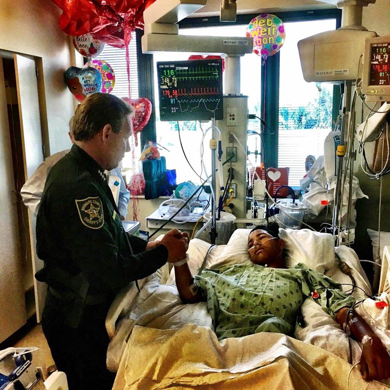 This image made available by the Broward County Sheriff's Office on Sunday, Feb. 18, 2018, shows Sheriff Scott Israel, holding the hand of Anthony Borges, 15, a student at Marjory Stoneman Douglas High School. The teenager was shot five times during the massacre on Valentine's Day that killed 17 students. Borges is being credited with saving the lives of at least 20 other students.