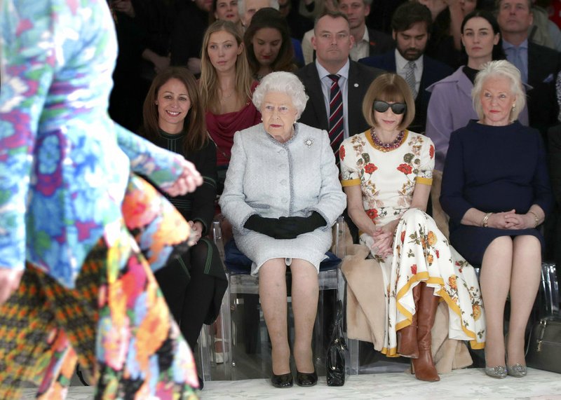 Britain's Queen Elizabeth, second left, sits next to fashion editor Anna Wintour, second right, and Caroline Rush, chief executive of the British Fashion Council (BFC), left, as they view Richard Quinn's runway show before presenting him with the inaugural Queen Elizabeth II Award for British Design, as she visits London Fashion Week's BFC Show Space in central London, Tuesday, Feb. 20, 2018. 