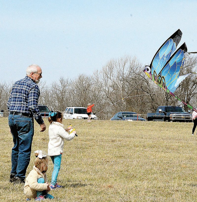 FILE PHOTO Michael Lorenz of Prairie Grove and his granddaughters, Remy and Kennedy Stearmen, fly a large dragonfly kite during the 2017 Cane Hill Kite Festival.