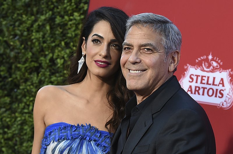 FILE - In this Oct. 22, 2017 file photo, Amal Clooney and George Clooney arrive at the premiere of "Suburbicon" in Los Angeles. George and Amal Clooney are donating $500,000 to students organizing nationwide marches against gun violence, and they say they'll also attend next month's planned protests. In a statement released Tuesday, Feb. 20, the couple says they are inspired by the "courage and eloquence" of the survivors-turned-activists from Stoneman Douglas High School in Parkland, Fla. (Photo by Jordan Strauss/Invision/AP, File)