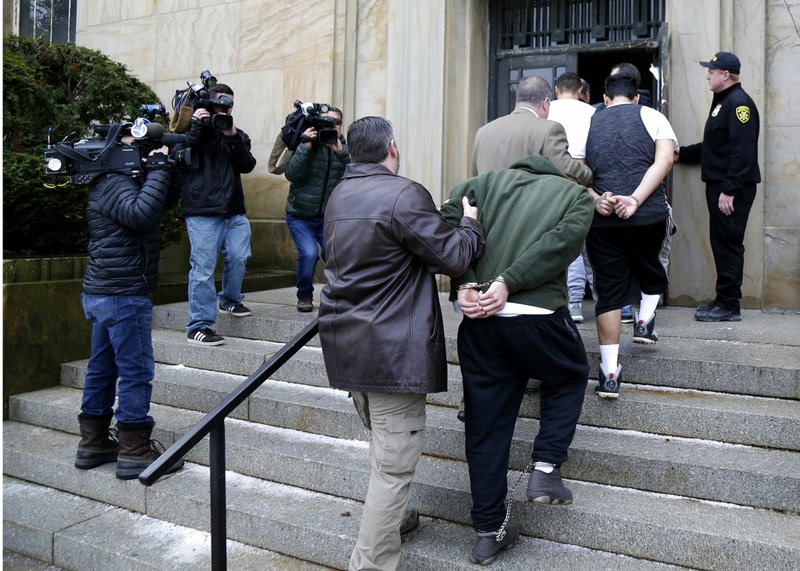 In this Jan. 11, 2018 file photo, suspected members of the MS-13 gang are escorted to their arraignment in Mineola, N.Y. A sweep of alleged MS-13 gang members on Long Island has racked up impressive arrest totals but also left unanswered questions. Since May, federal authorities say they've arrested more than 220 members of the notorious street gang. But authorities have largely declined multiple requests by for even the most basic information about the arrests.