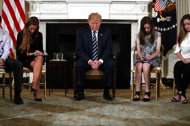 President Donald Trump bows his head during an opening prayer at the start of a listening session with high school students and teachers in the State Dining Room of the White House in Washington, Wednesday, Feb. 21, 2018. 