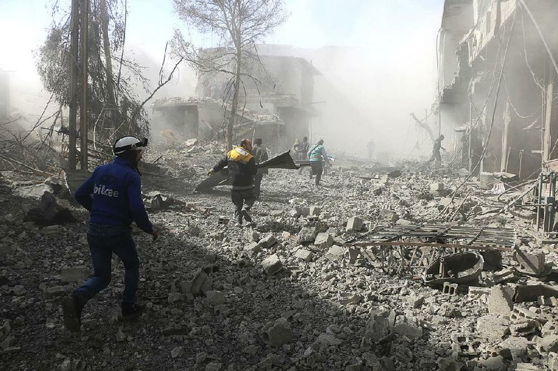 Volunteer first responders run to help survivors Tuesday in the Damascus suburb of Ghouta, where Syrian government airstrikes and artillery attacks have killed scores of people in two days. Opposition forces retaliated with mortar fire on Damascus, causing panic in the seat of President Bashar Assad’s power.    