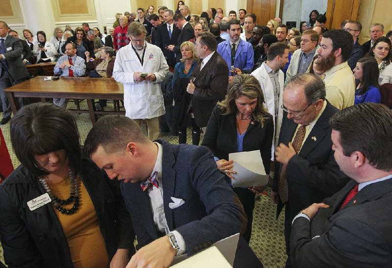 Arkansas Pharmacists Association staff members Elisabeth Mathews (left) and Jordan Foster prepare for a presentation in the Old Supreme Court Room of the Capitol as Rep. Michelle Gray (center), Sen. Ron Caldwell and Sen. Jason Rapert look over their notes. Gray and Caldwell are sponsoring legislation on pharmacy benefits managers.