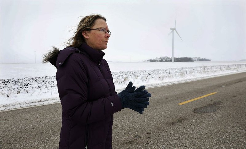 Dorenne Hansen of Glenville, Minn., stands on a rural highway near a wind turbine in a field near Northwood, Iowa, in January. Opponents of wind power are successfully stalling or rejecting wind-farm projects across the country. 